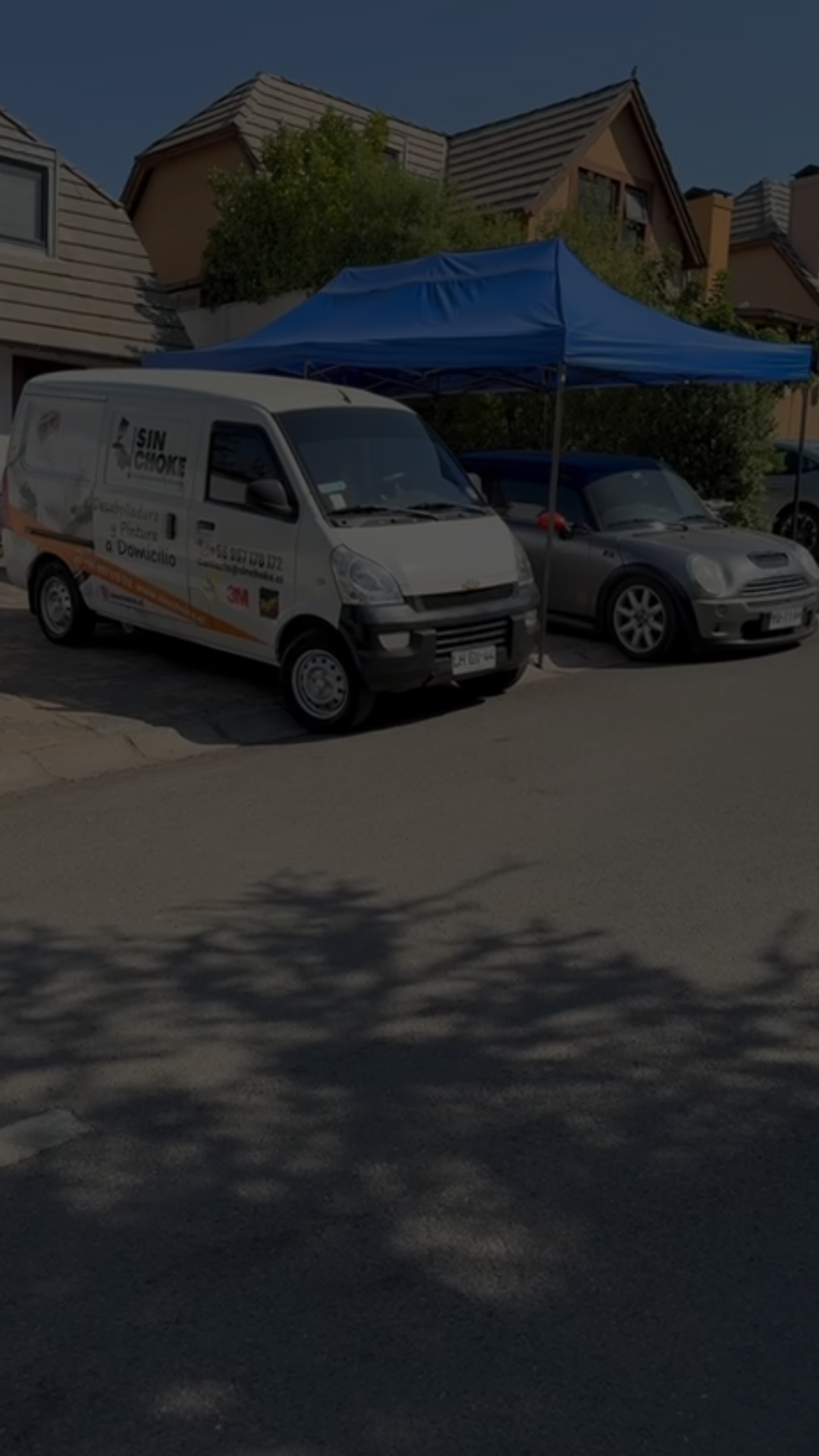 Técnico pintando un auto azul en cabina